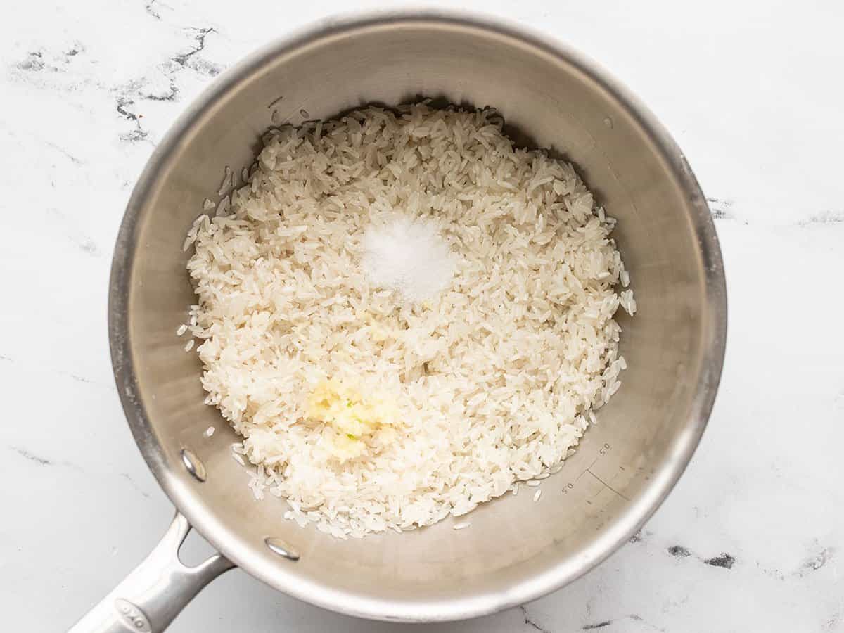 Washed rice with minced garlic and salt in a saucepan.