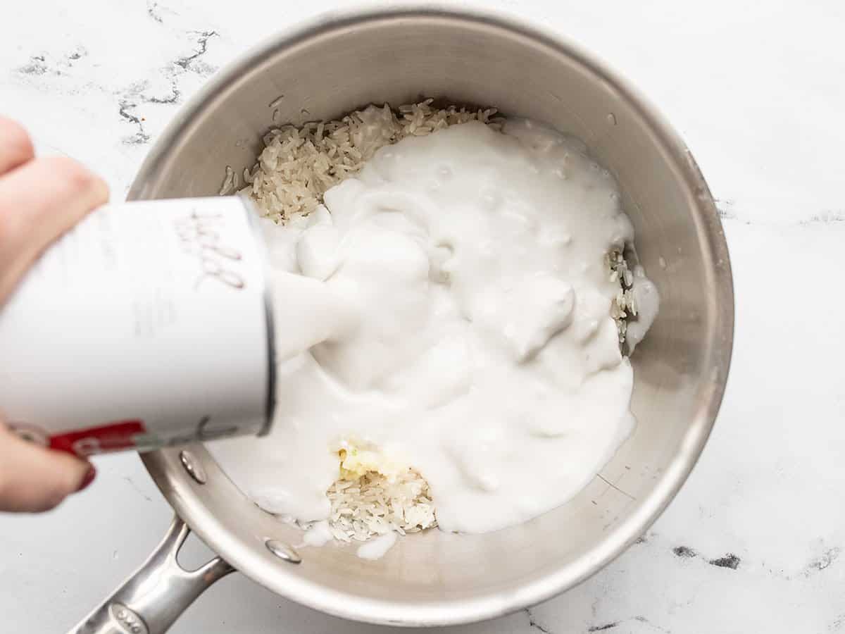 Coconut milk being poured into the saucepot.