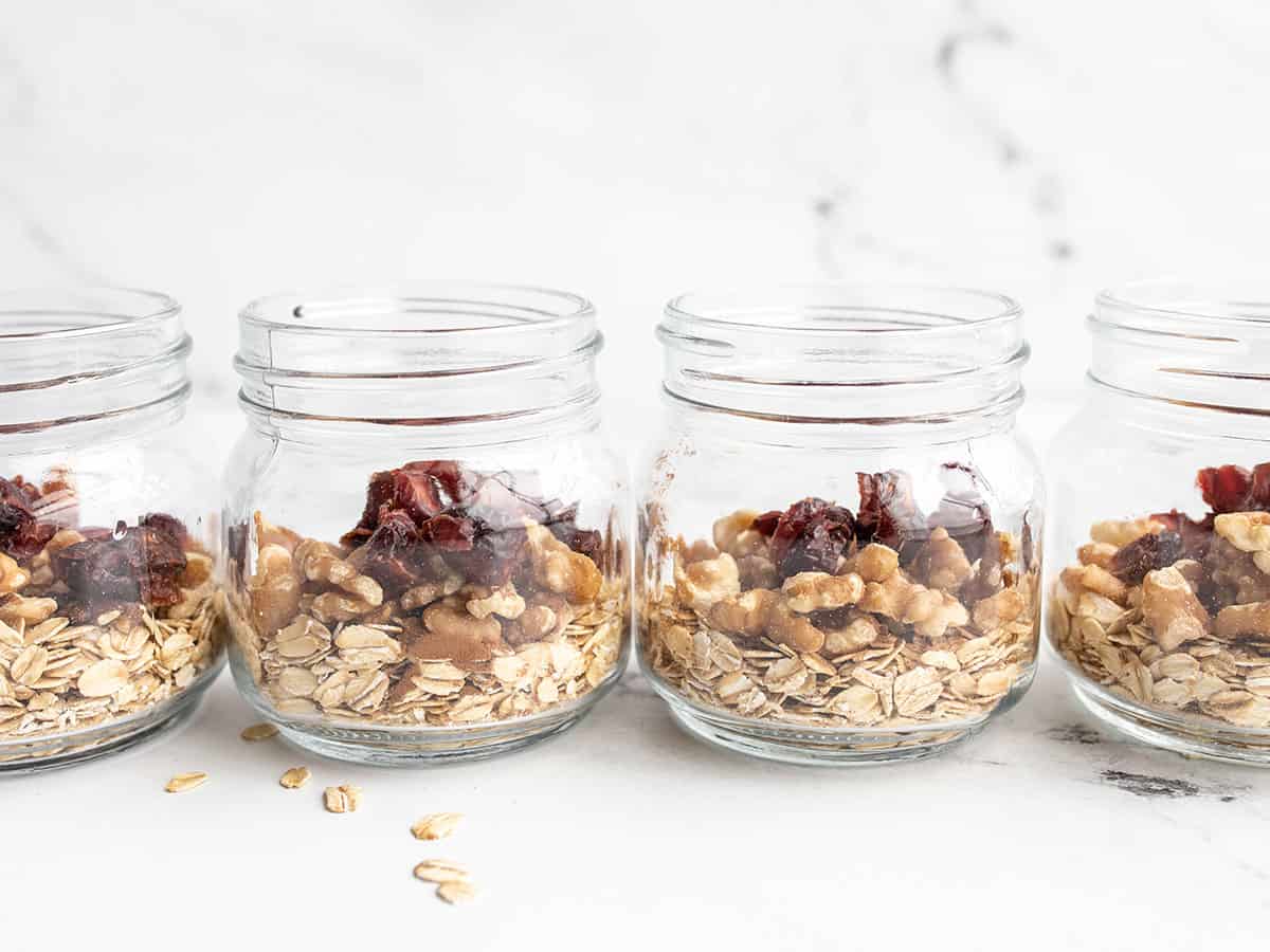 Walnuts and dried fruit added to the jars, from the side.