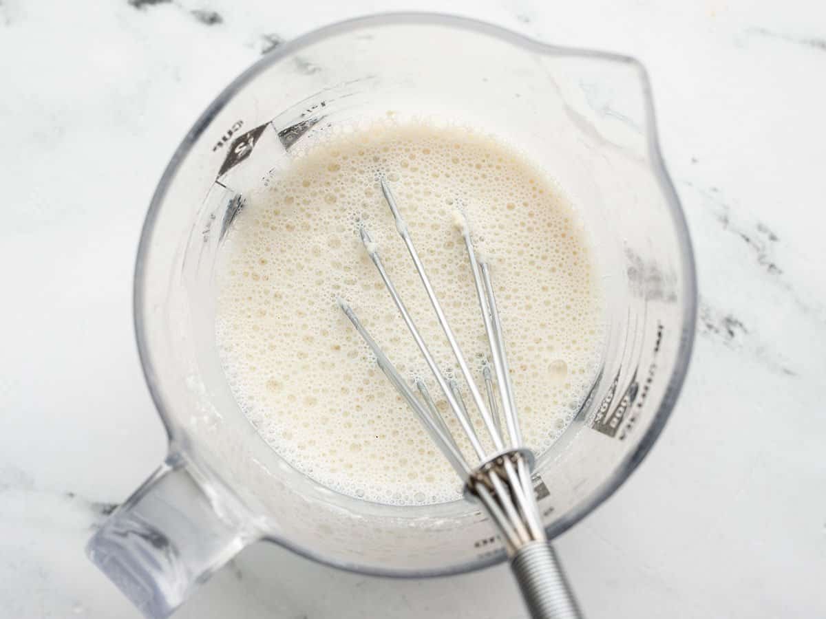 Milk in a measuring cup with a whisk.