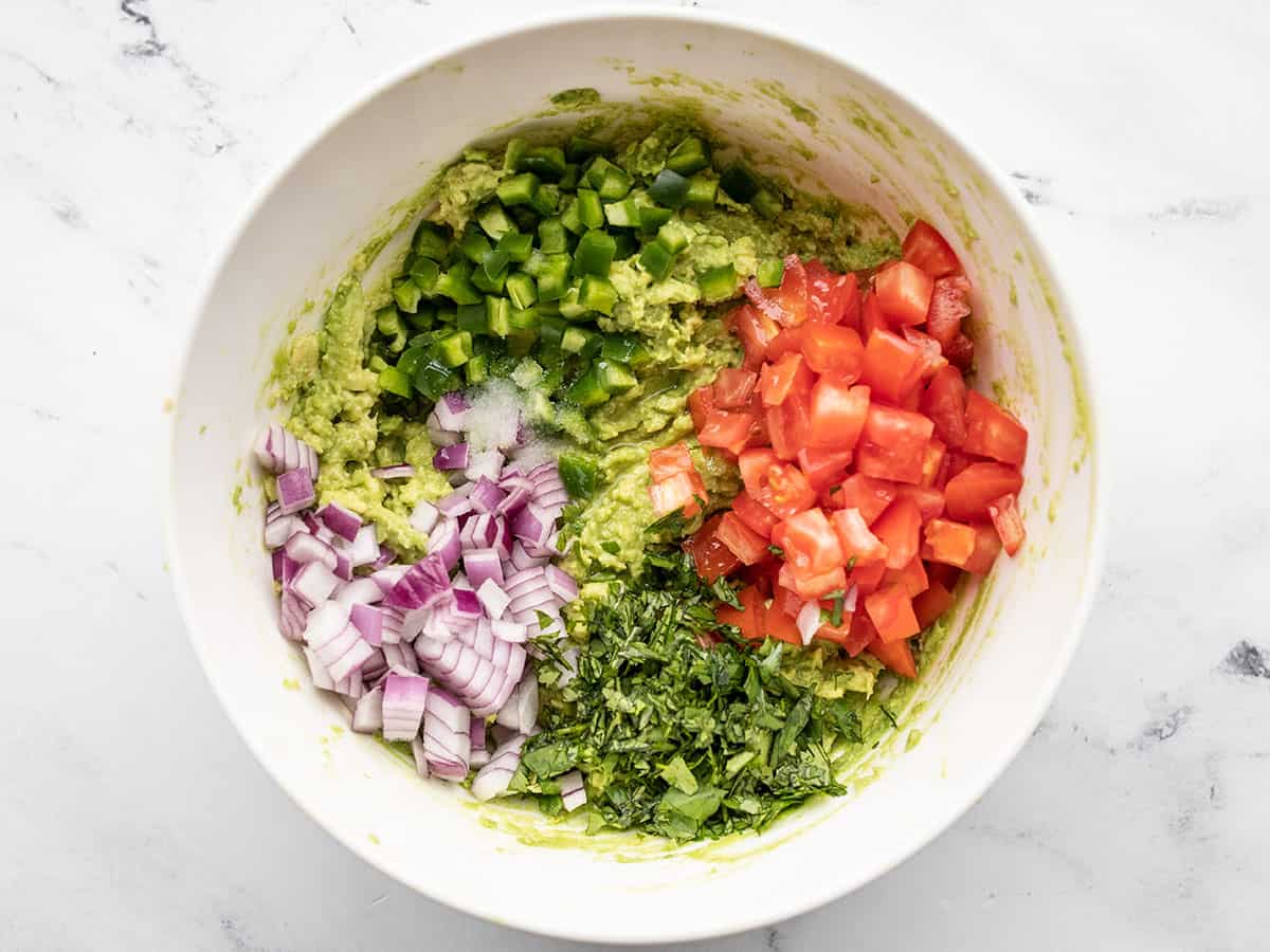 Other ingredients added to the mashed avocado in the bowl.