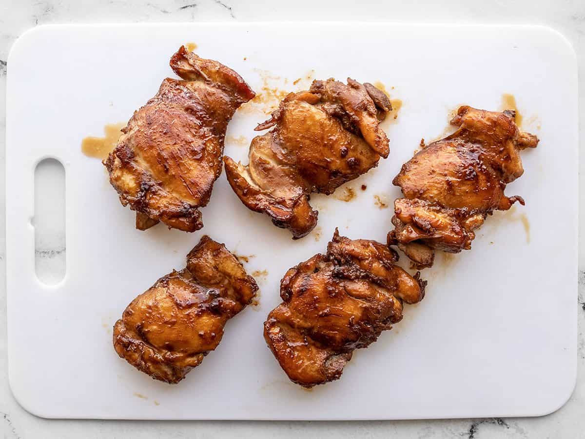 Finished teriyaki chicken thighs on a cutting board.