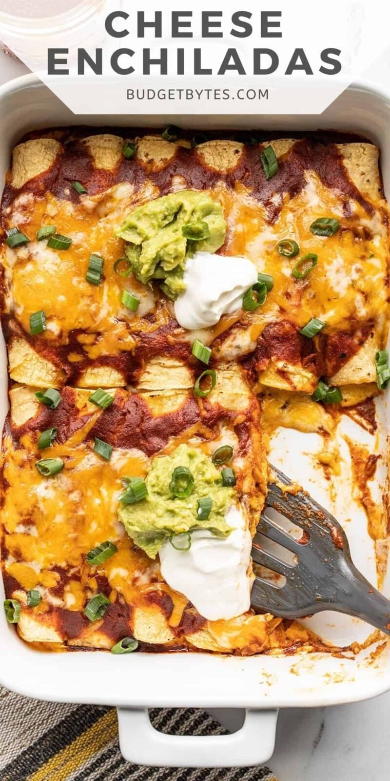 Overhead view of a casserole dish full of cheese enchiladas with a spatula.