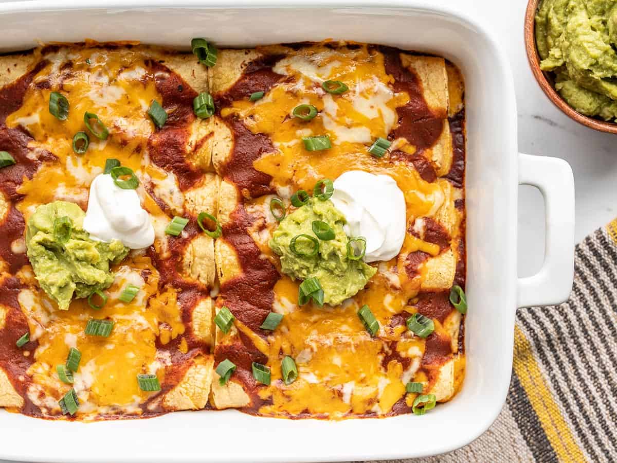 Close up view of a casserole dish full of cheese enchiladas.