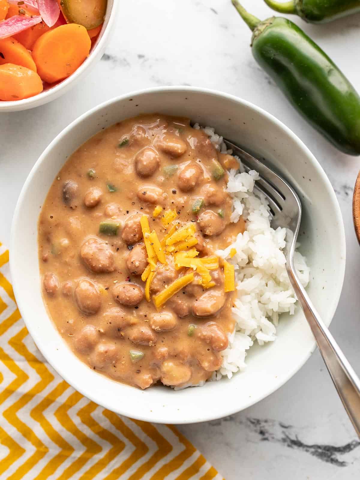 A bowl of cheesy pinto beans over rice.