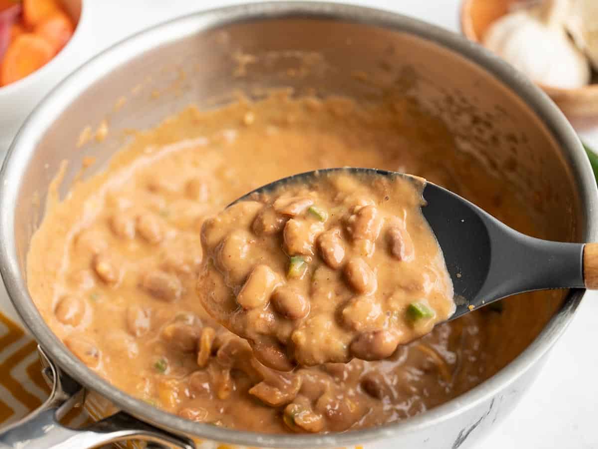 Cheesy Pinto Beans on a serving spoon in the pot.