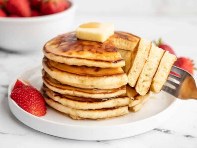 Side view of a stack of pancakes with a fork.