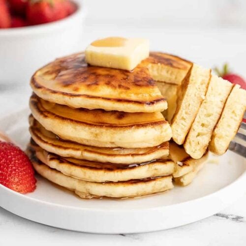 Side view of a stack of pancakes with a fork.