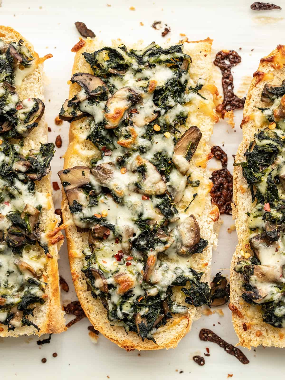 Close up overhead view of spinach mushroom french bread pizzas.