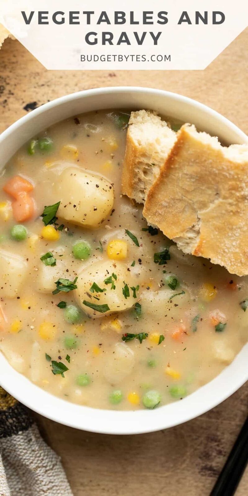 Overhead view of a bowl of vegetables with gravy and a piece of bread.