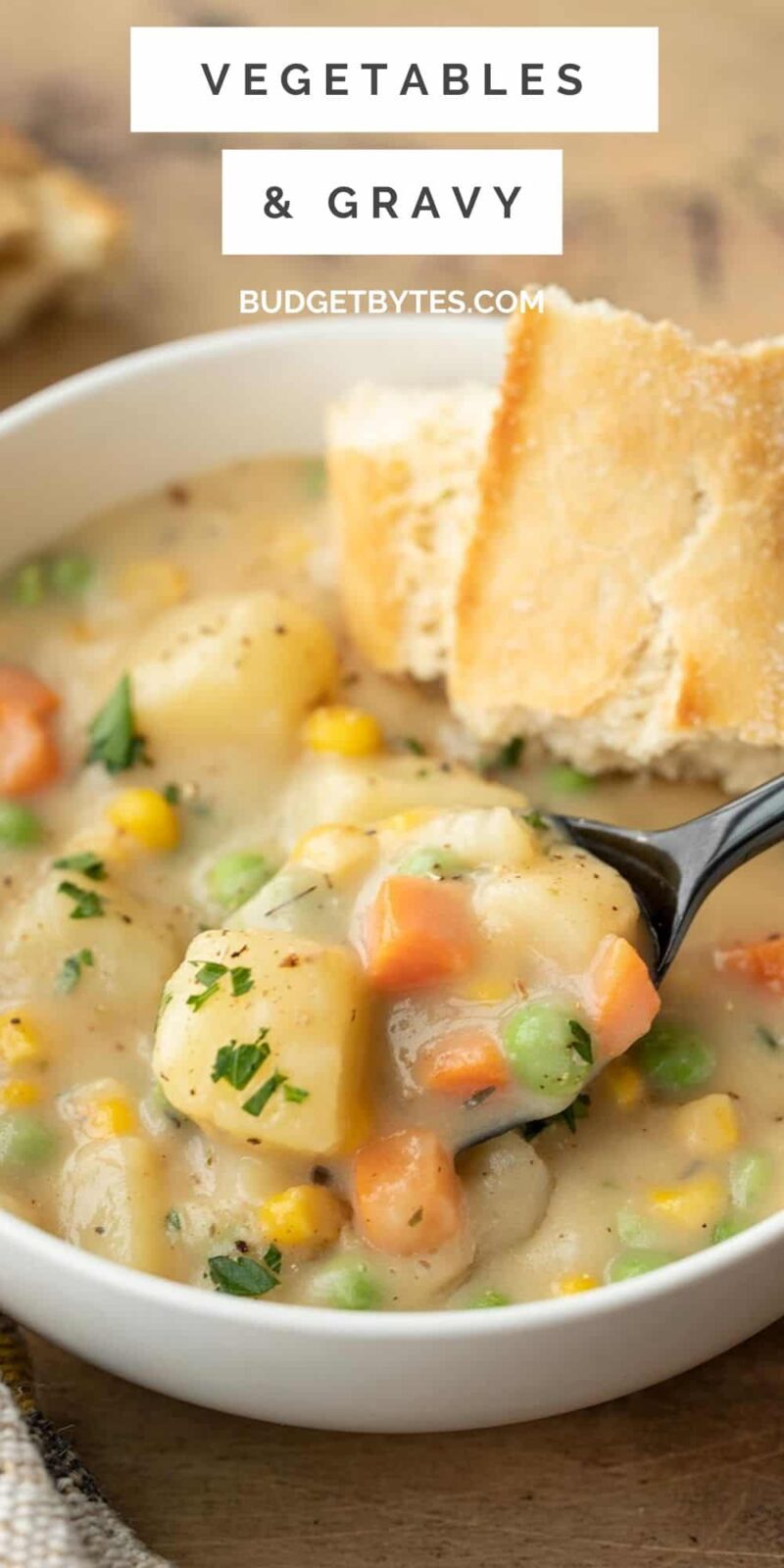 side view of a bowl of vegetables and gravy with a spoon being lifted from the bowl.