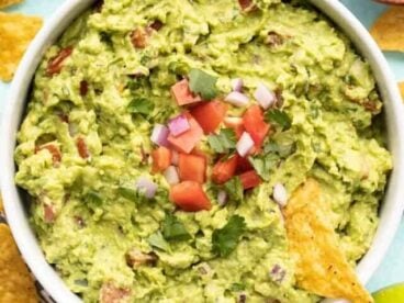 close up of guacamole in the bowl with a chip.