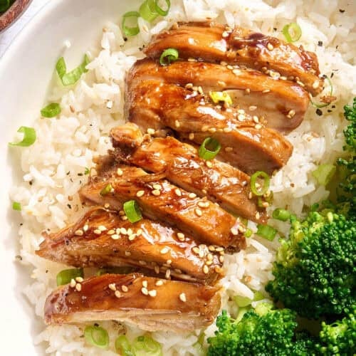 Overhead view of sliced teriyaki chicken on a bed on rice on a plate.