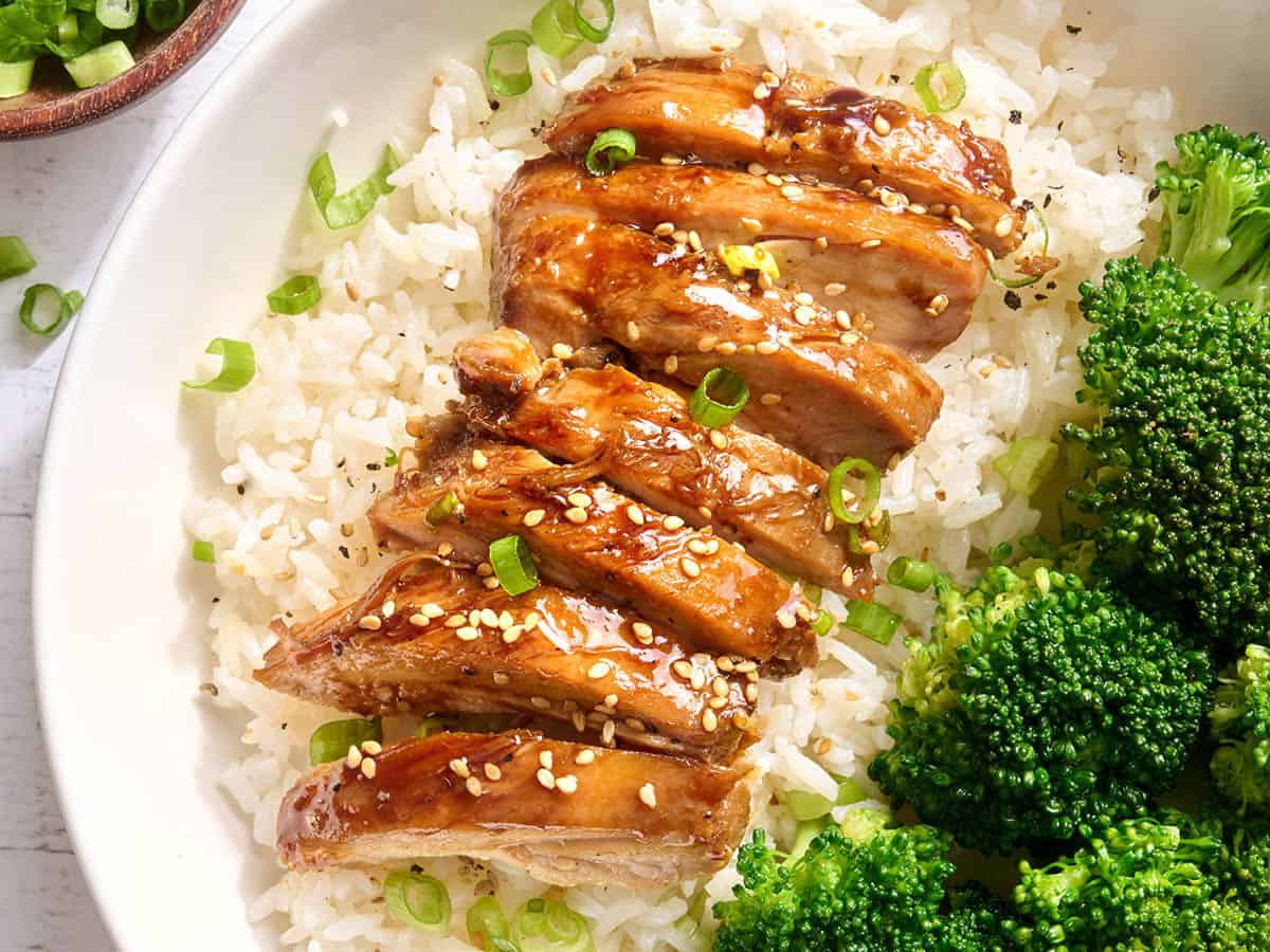 Overhead view of sliced teriyaki chicken on a bed on rice on a plate.