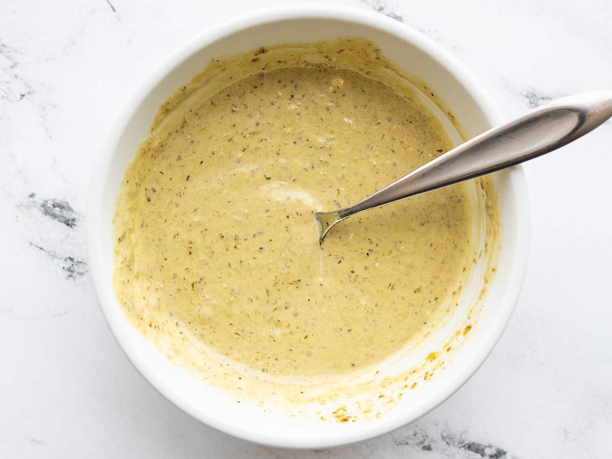 Creamy pesto dressing in a bowl with a spoon.