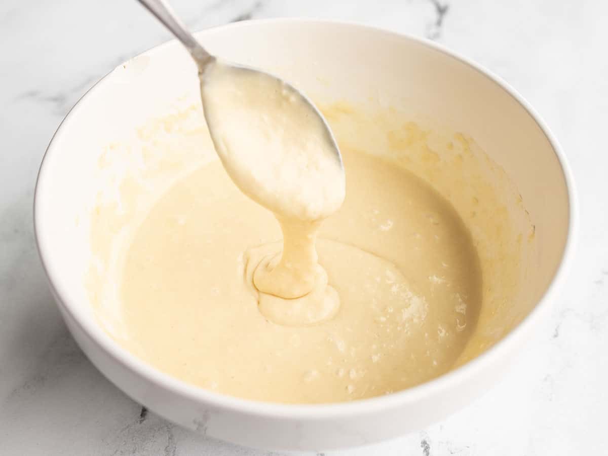 Pancake batter pouring off a spoon into a bowl.