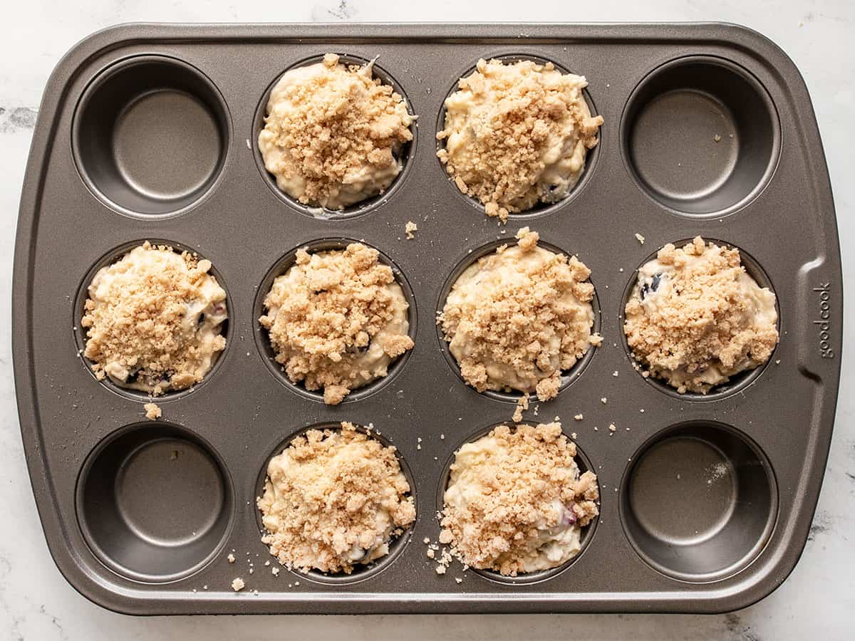 Muffins de mirtilo não cozidos na forma de muffin coberto com crumble.