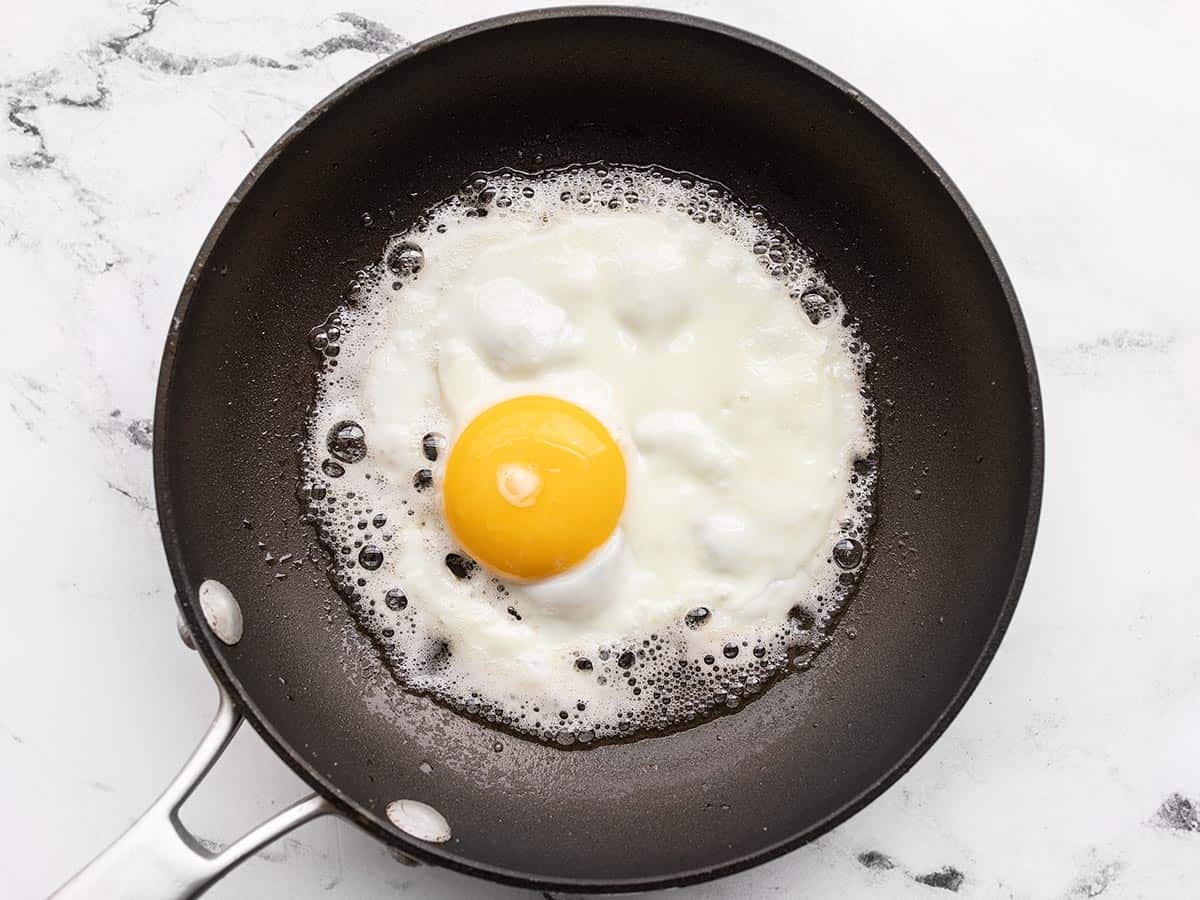 A sunny side up egg being fried in bacon fat.