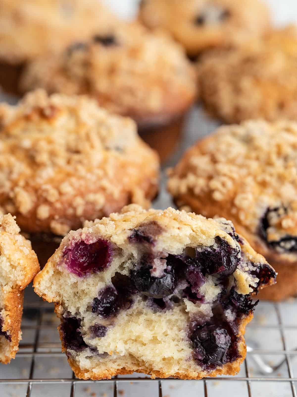 Muffins de mirtilo em um rack de resfriamento com o primeiro rasgado.