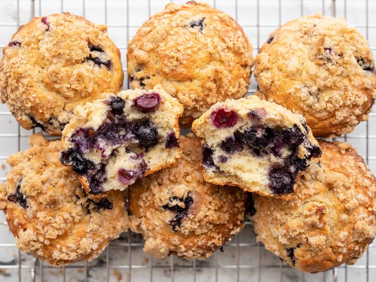 Vista aérea de muffins de mirtilo em um rack de resfriamento com um rasgado ao meio. 