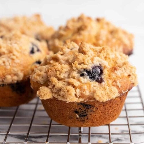 Side view of blueberry muffins on a cooling rack.