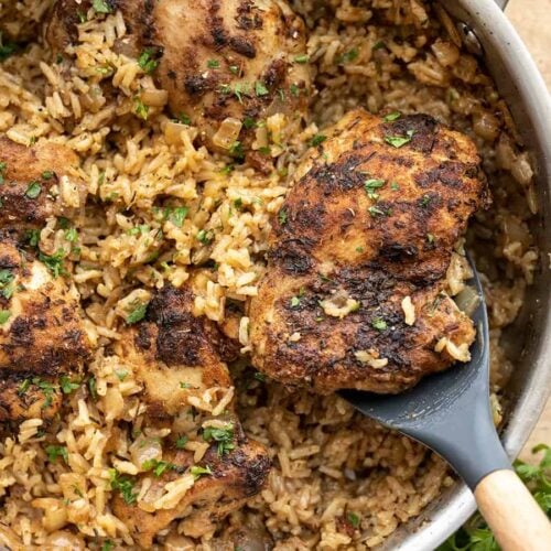 Close up of chicken being scooped out of the skillet.