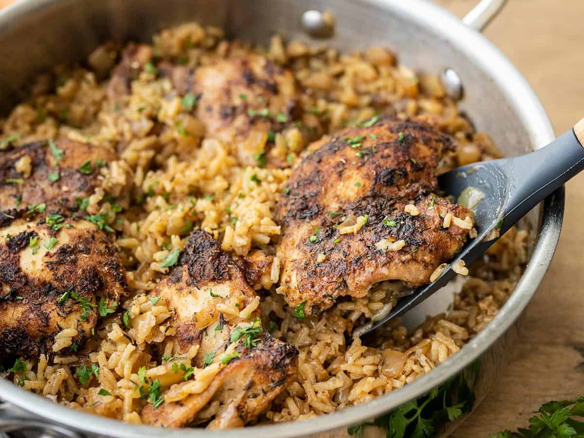 Side view of chicken being scooped out of the skillet.