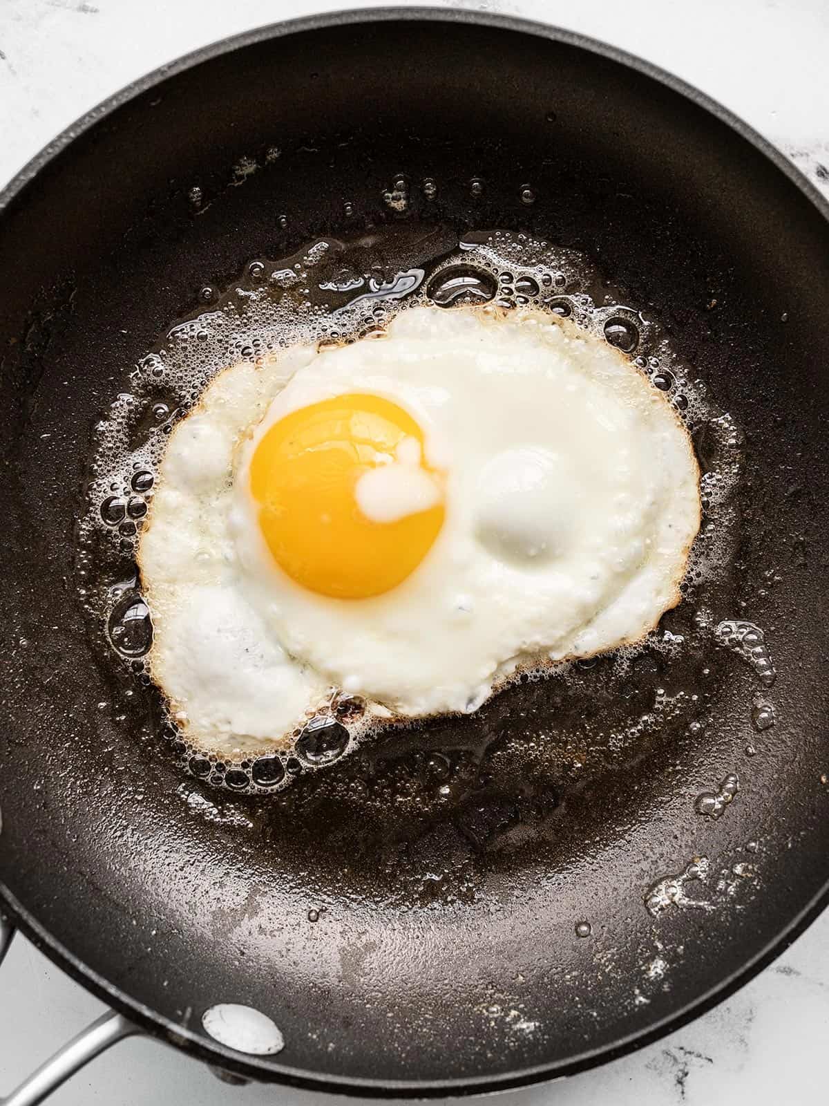 Close up overhead view of a sunny side up egg in a frying pan.