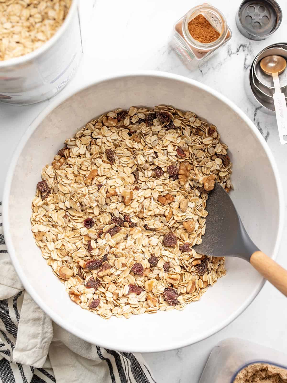 A batch of muesli in a bowl with ingredients on the sides. 