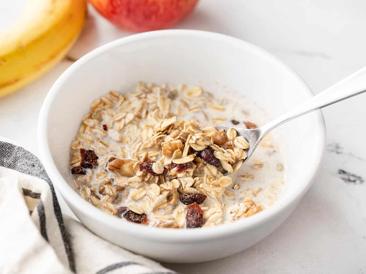 Side view of a bowl of muesli with milk and a spoon.
