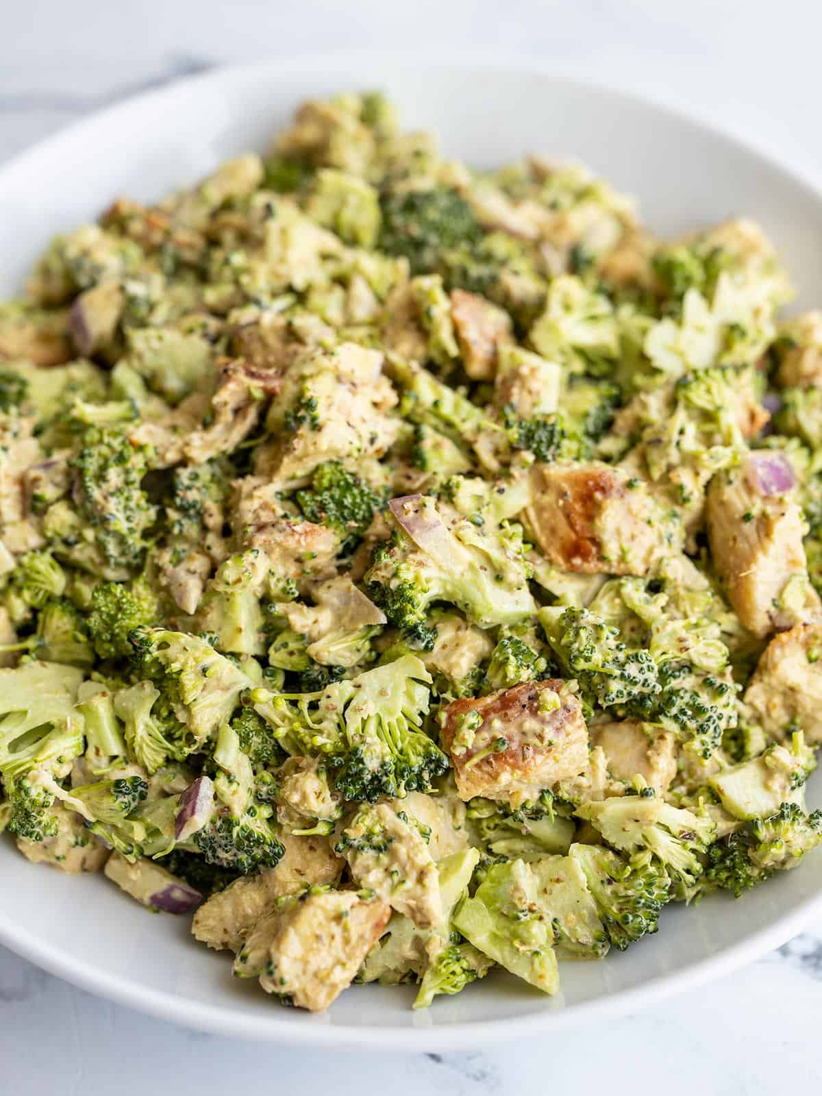 Close up side view of pesto chicken broccoli salad in a bowl.
