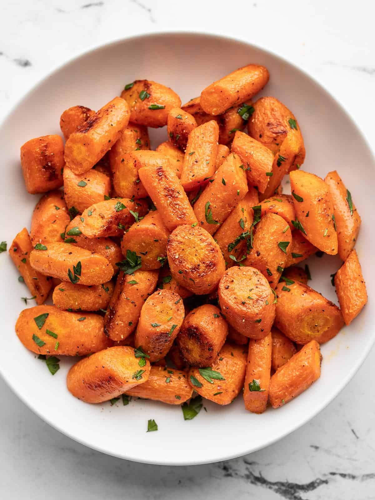 roasted carrots garnished with parsley in a bowl.