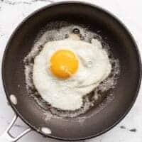 A sunny side up egg being fried in butter