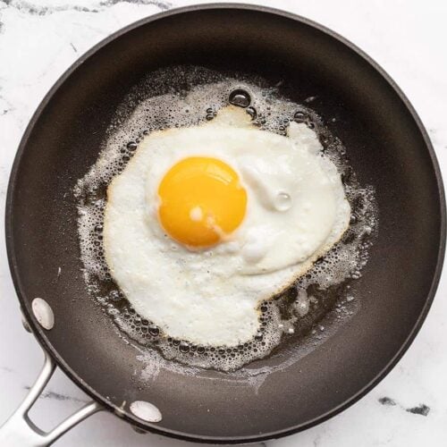 A sunny side up egg being fried in butter