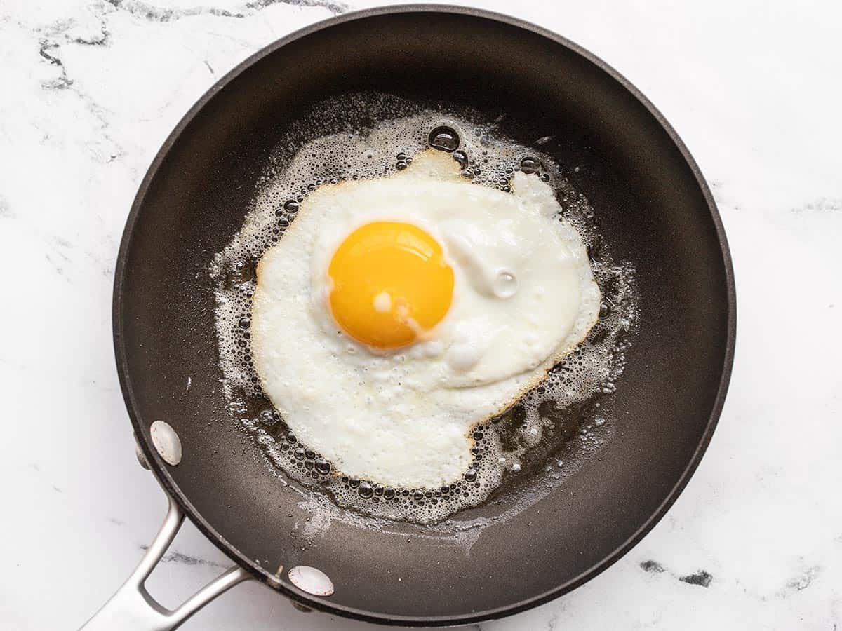 A sunny side up egg being fried in butter