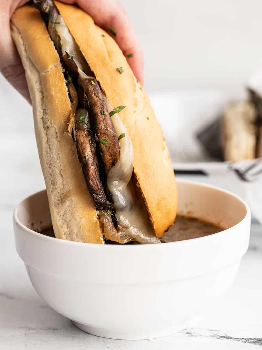 Vegetarian French sandwich dipped in au jus bowl.