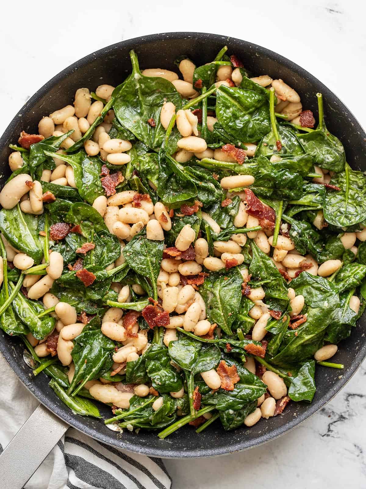 overhead view of wilted spinach salad in the skillet.