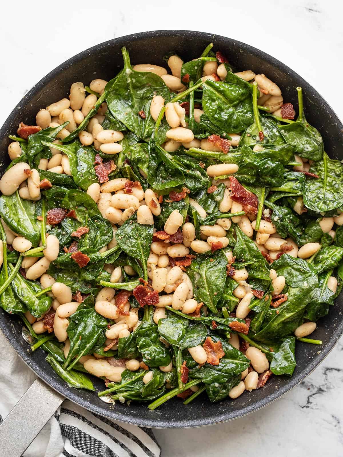 visão aérea da salada de espinafre murcha na frigideira.