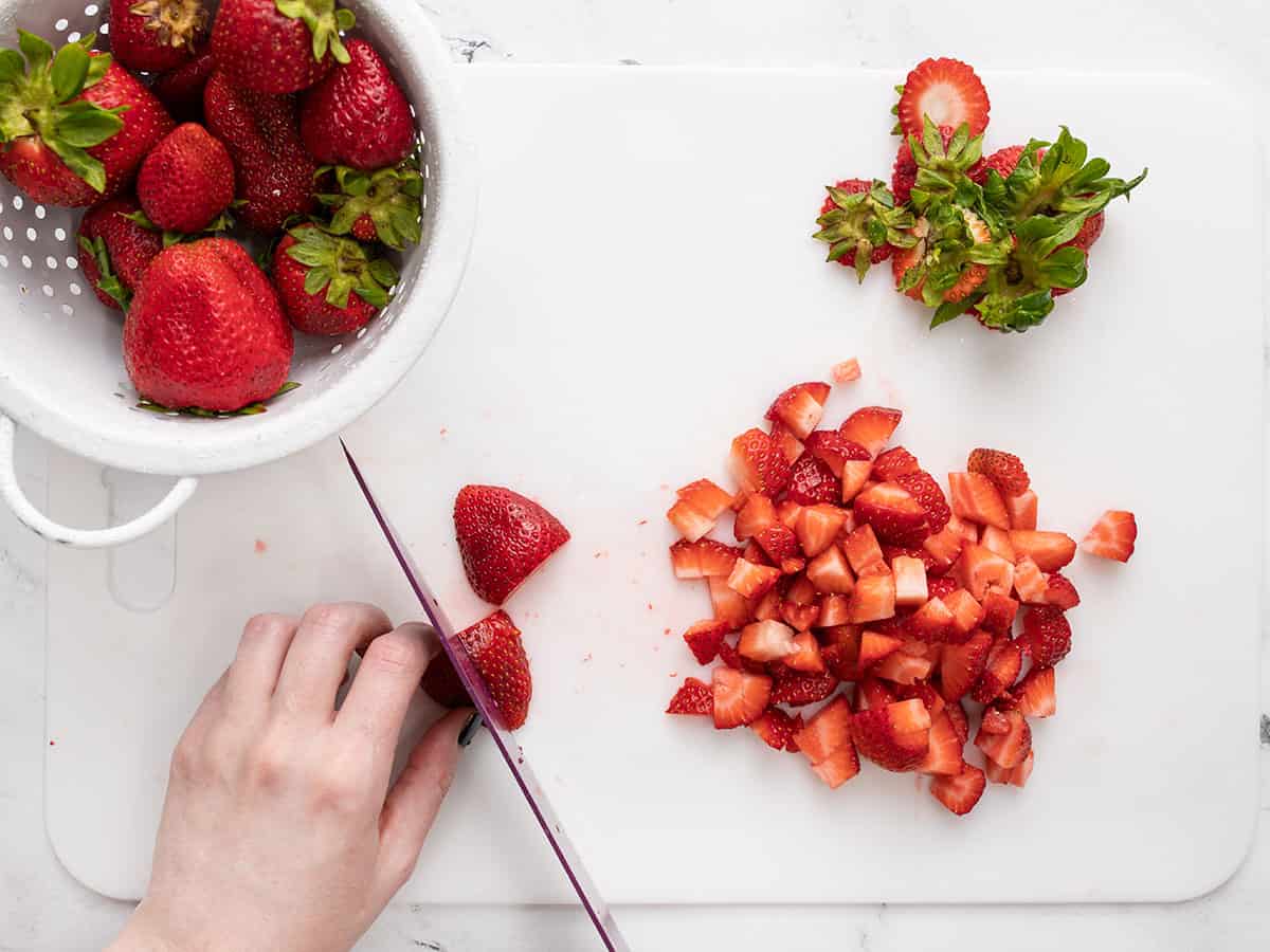 Strawberries being chopped into quarter inch pieces.