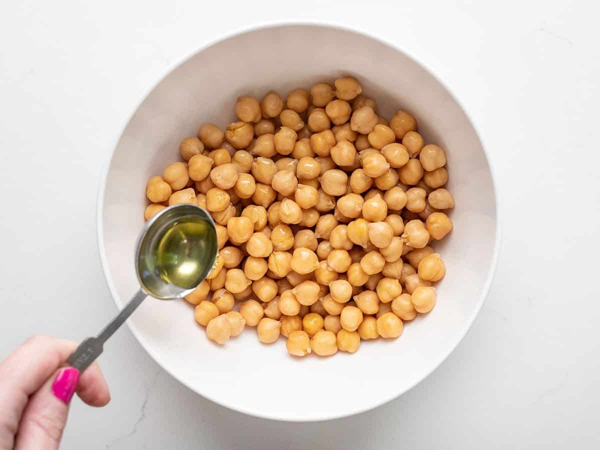 Oil being drizzled over chickpeas.