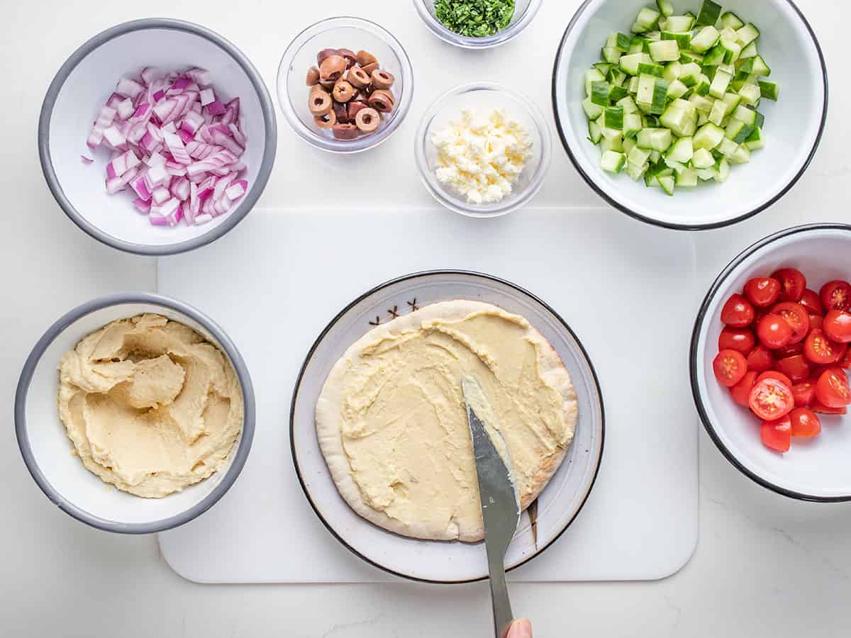 Pita with a quarter cup of hummus spread on it.