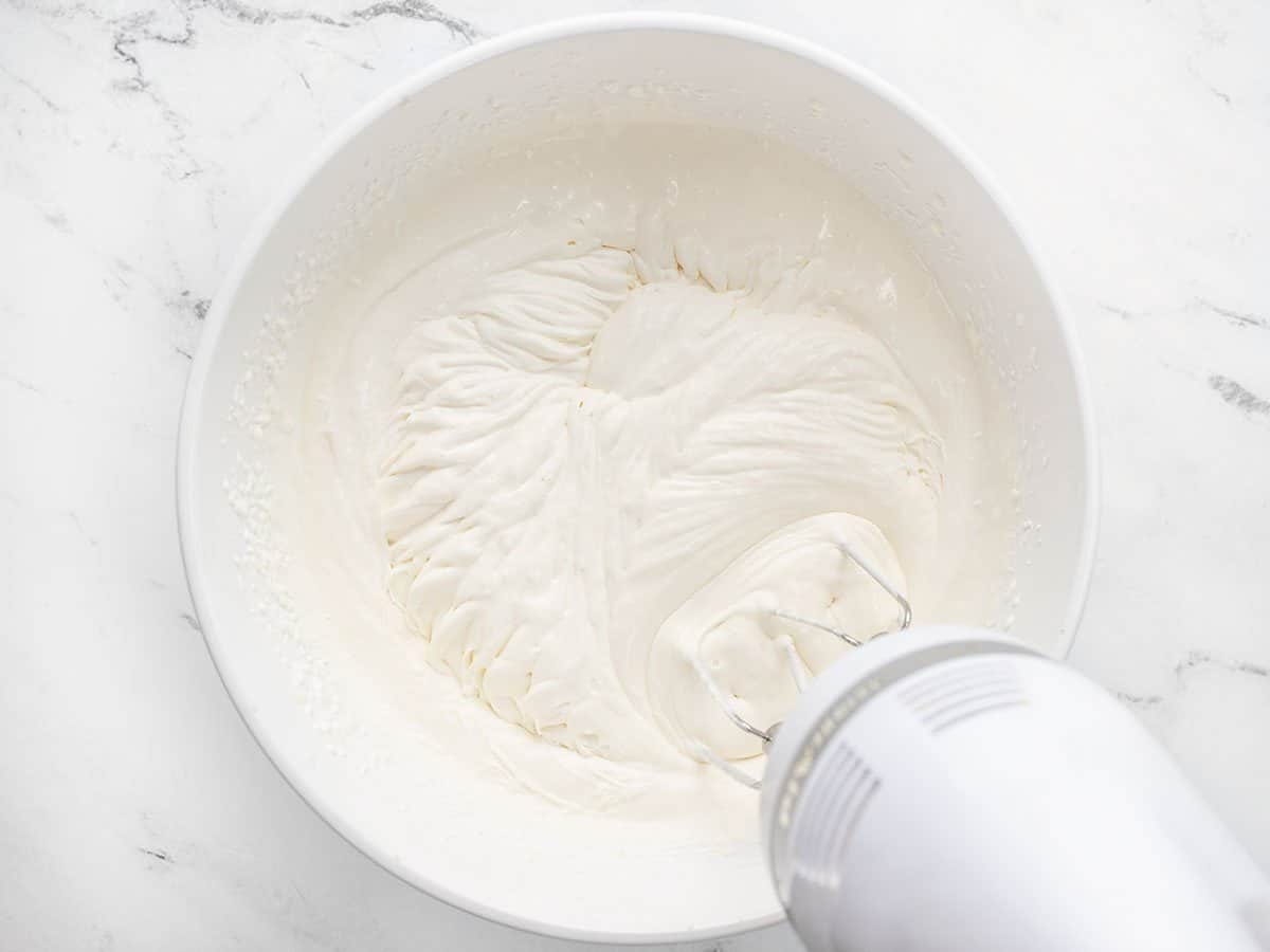 Whipping heavy cream mixture into soft peaks.