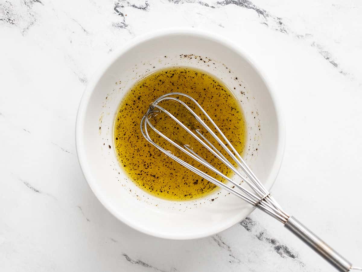 Lemony dressing in a bowl with a whisk.