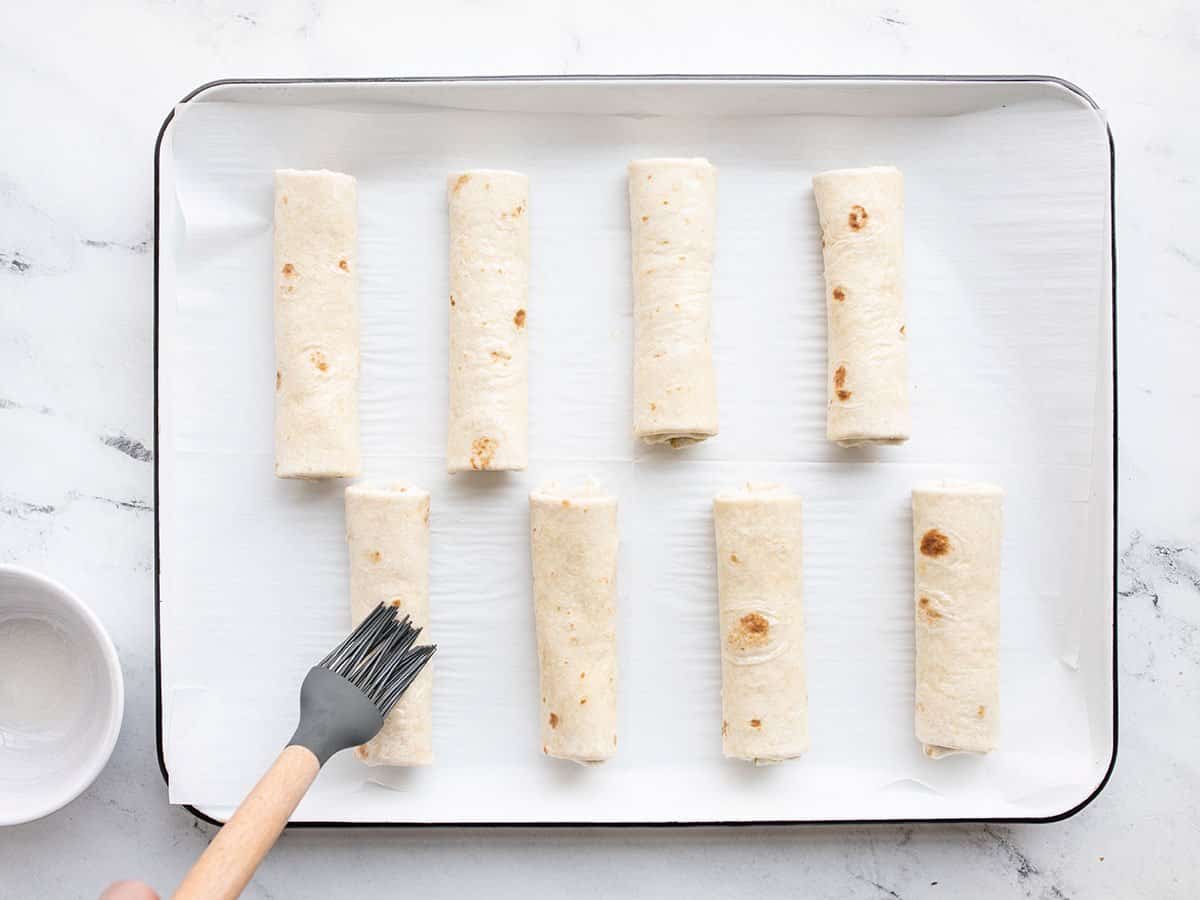 pesto mozzarella roll ups being brushed with oil.