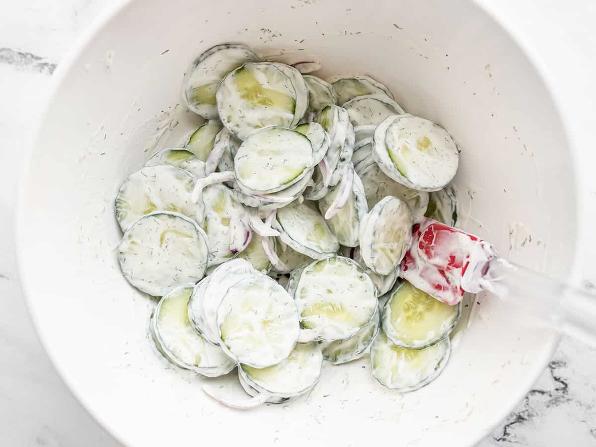 Finished cucumber salad in a bowl with a spatula.