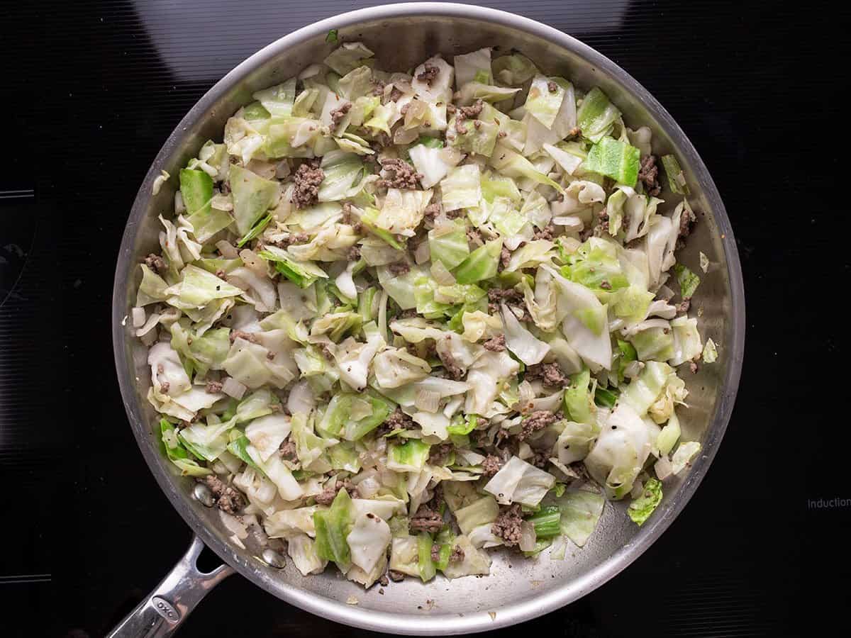Softened cabbage mixed with beef and onion in the skillet.