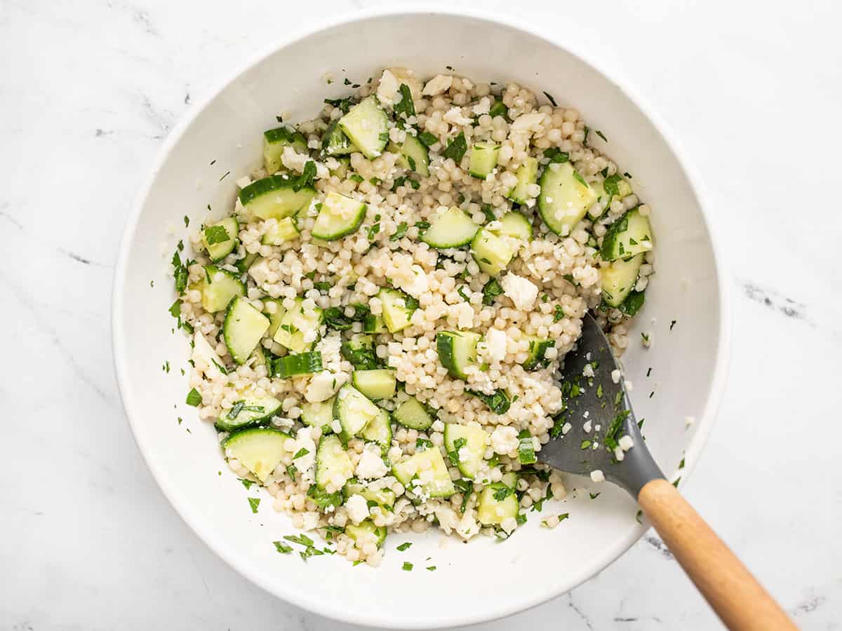 Finished lemony cucumber couscous salad in the bowl with a large spoon.