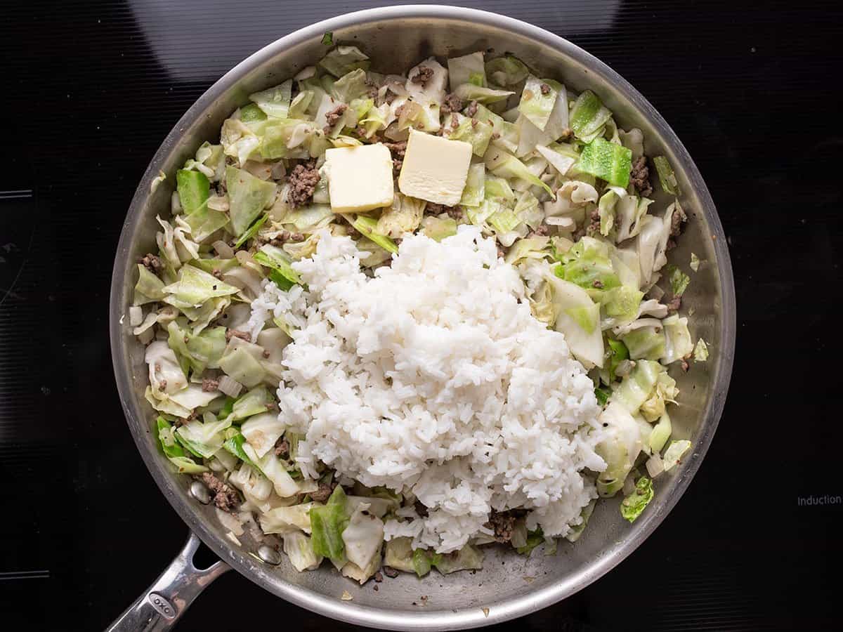 Arroz cozido e manteiga adicionados à frigideira.