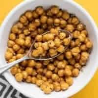 Close up overhead view of a bowl full of air fryer chickpeas with a spoon.