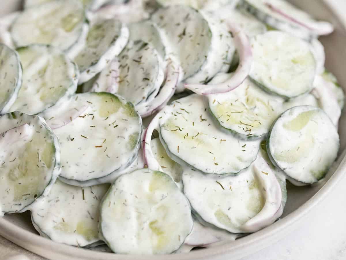 Close up side view of creamy cucumber salad in a bowl.